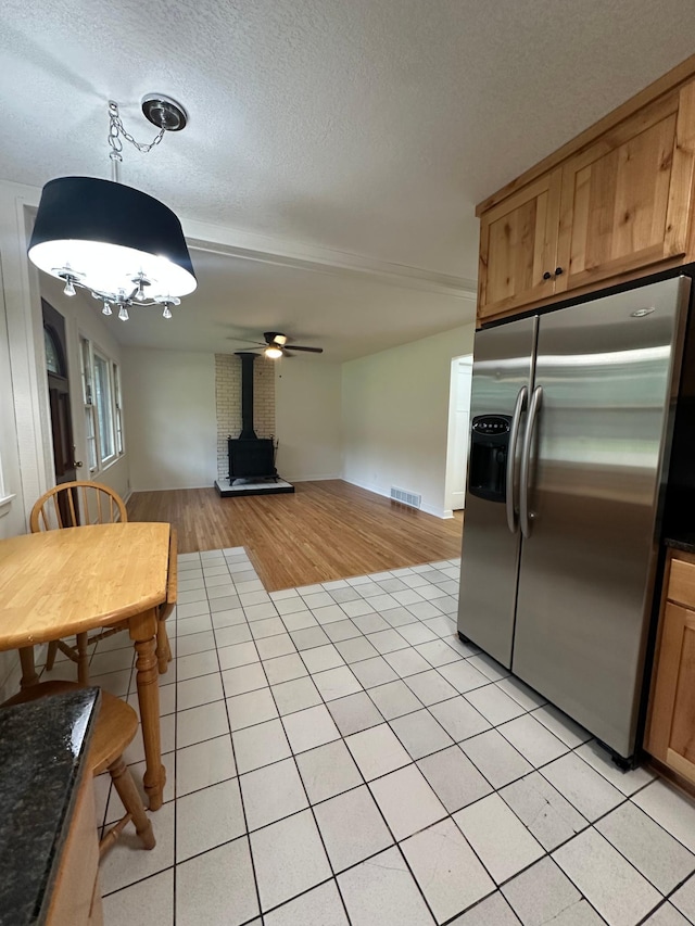 2325 Crosstown Blvd NE, Ham Lake, MN 55304 - kitchen with stainless steel fridge, a wood stove, light tile patterned floors, dark countertops, and a textured ceiling