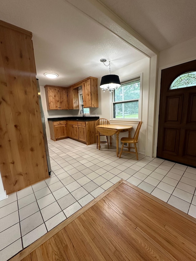 2325 Crosstown Blvd NE, Ham Lake, MN 55304 - kitchen featuring brown cabinetry, dark countertops, light tile patterned flooring, and a chandelier