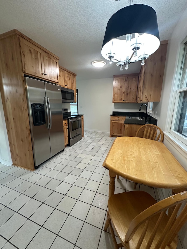 2325 Crosstown Blvd NE, Ham Lake, MN 55304 - kitchen featuring appliances with stainless steel finishes, a textured ceiling, dark countertops, a chandelier, and light tile patterned flooring