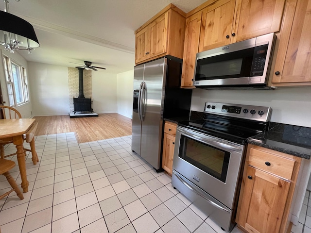 2325 Crosstown Blvd NE, Ham Lake, MN 55304 - kitchen featuring appliances with stainless steel finishes, a wood stove, open floor plan, light tile patterned flooring, and a ceiling fan