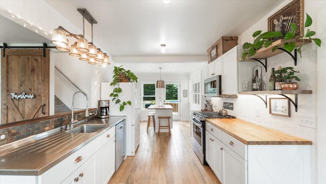 21038 Lace Ave, Hutchinson, MN 55350 - kitchen with appliances with stainless steel finishes, open shelves, a barn door, light wood-type flooring, and tasteful backsplash
