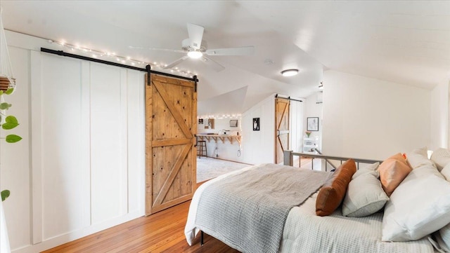 21038 Lace Ave, Hutchinson, MN 55350 - bedroom featuring a barn door, light wood-type flooring, and lofted ceiling