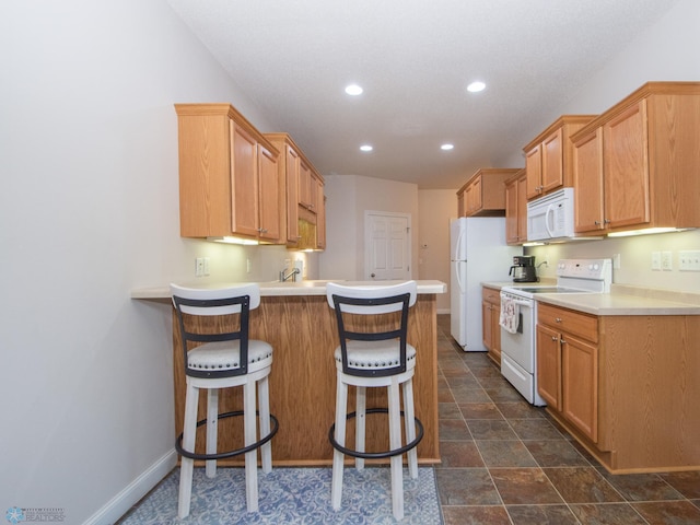 508 19th Ave W Unit C, West Fargo, ND 58078 - kitchen with white appliances, a peninsula, recessed lighting, a kitchen breakfast bar, and light countertops