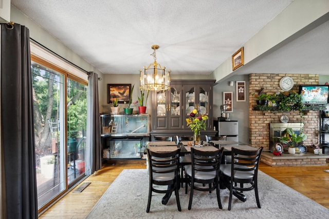 1613 Lyn Curve Ave N, Minneapolis, MN 55411 - dining room with wood finished floors, a textured ceiling, a chandelier, and a fireplace