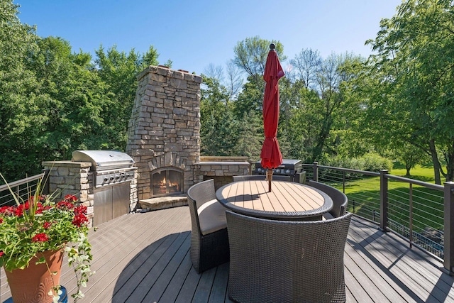 849 Brown Rd N, Orono, MN 55356 - wooden deck featuring an outdoor stone fireplace, an outdoor kitchen, outdoor dining space, and view of wooded area
