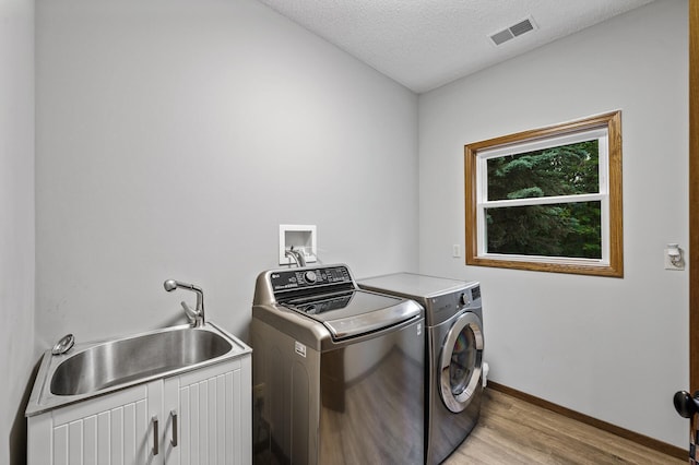 2801 263rd Ave NE, Isanti, MN 55040 - laundry room with washer and dryer, light wood-style floors, cabinet space, and a textured ceiling