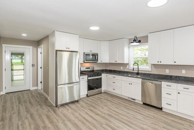 26877 Rainbow Ln, Merrifield, MN 56465 - kitchen featuring appliances with stainless steel finishes, light wood finished floors, white cabinetry, recessed lighting, and dark stone counters