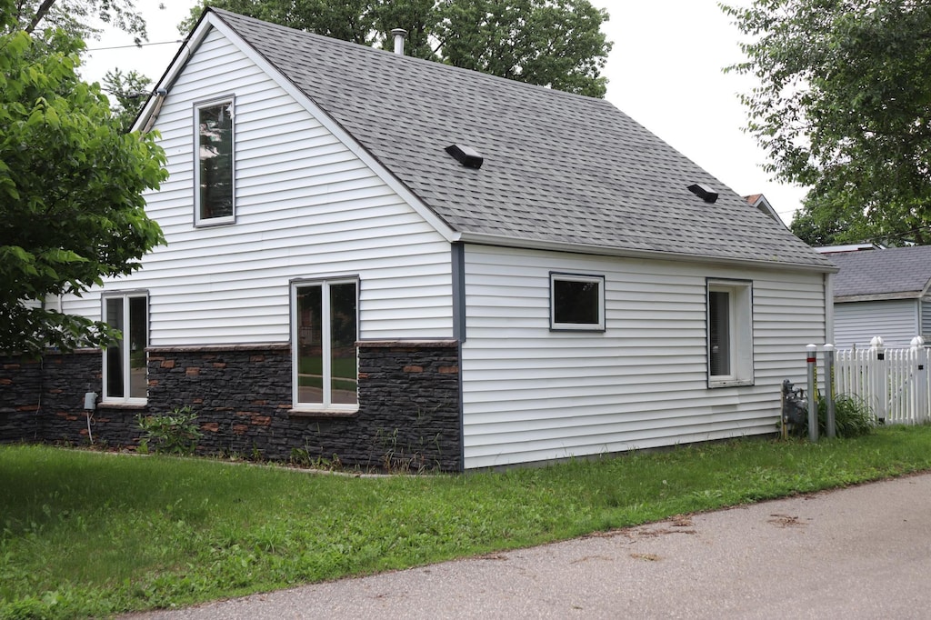 511 3rd St NE, Saint Cloud, MN 56304 - view of side of home featuring a shingled roof and stone siding