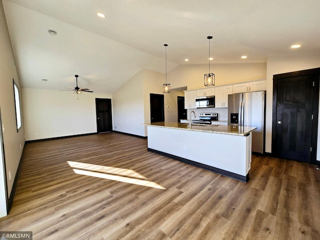 2003 Essler Dr, Saint Peter, MN 56082 - kitchen featuring appliances with stainless steel finishes, white cabinetry, vaulted ceiling, light stone counters, and an island with sink