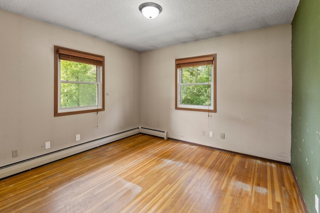 7 Pleasant Ave SE, Remer, MN 56672 - empty room with wood finished floors, plenty of natural light, a textured ceiling, and a baseboard heating unit