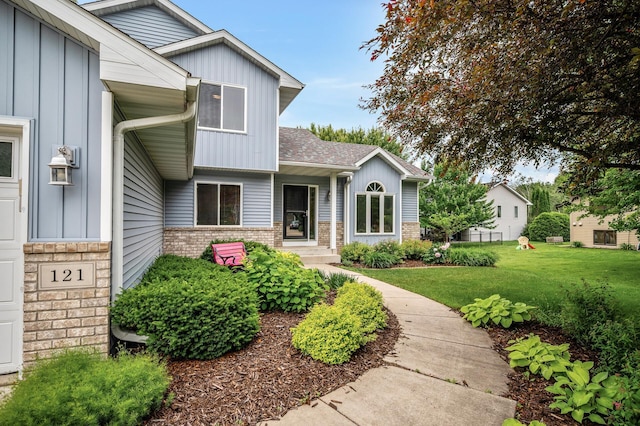 121 Arbor St, Northfield, MN 55057 - property entrance featuring board and batten siding, brick siding, a lawn, and a shingled roof