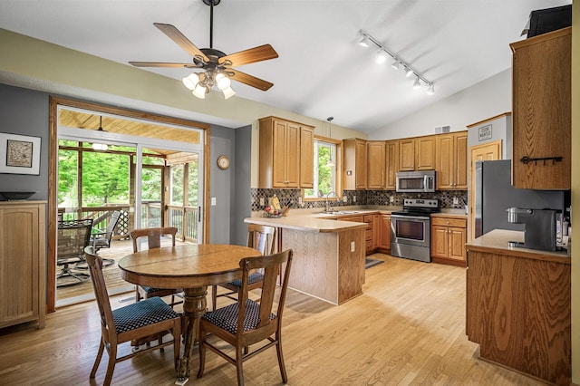121 Arbor St, Northfield, MN 55057 - kitchen with appliances with stainless steel finishes, track lighting, a peninsula, lofted ceiling, and decorative backsplash