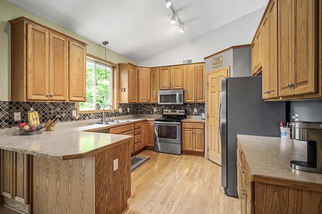 121 Arbor St, Northfield, MN 55057 - kitchen with appliances with stainless steel finishes, a peninsula, light wood-style floors, decorative backsplash, and vaulted ceiling