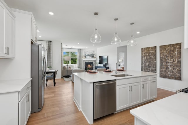 15165 Quince St NW, Andover, MN 55304 - kitchen featuring stainless steel appliances, a stone fireplace, a center island with sink, light countertops, and recessed lighting