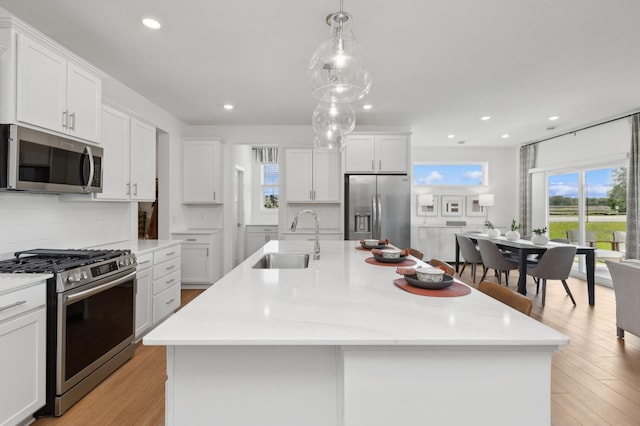 15165 Quince St NW, Andover, MN 55304 - kitchen with appliances with stainless steel finishes, a center island with sink, white cabinetry, light wood finished floors, and recessed lighting