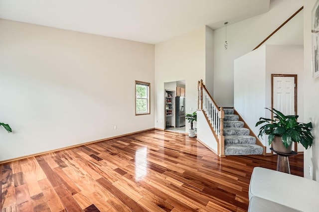 6788 Carlisle Curv, Shakopee, MN 55379 - unfurnished living room featuring stairway, a high ceiling, and wood finished floors