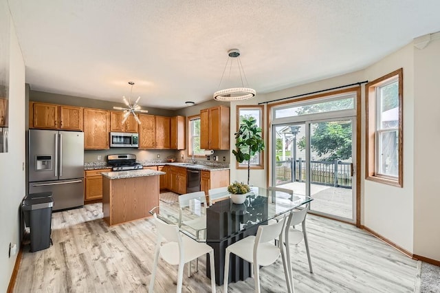 6788 Carlisle Curv, Shakopee, MN 55379 - kitchen featuring stainless steel appliances, light wood-style flooring, a kitchen island, and brown cabinetry