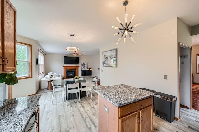 6788 Carlisle Curv, Shakopee, MN 55379 - kitchen with light wood finished floors, a glass covered fireplace, a chandelier, and brown cabinetry