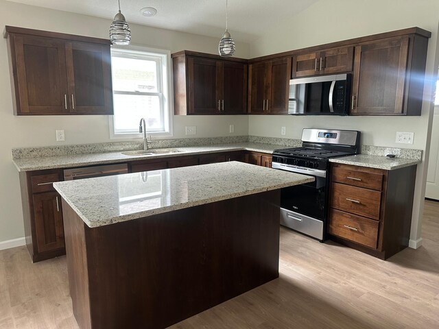 720 Cherrywood Ln NE, Isanti, MN 55040 - kitchen featuring stainless steel appliances, light wood finished floors, a center island, dark brown cabinetry, and light stone countertops