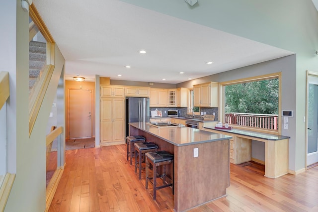 10902 Eagle Lake Blvd, Maple Grove, MN 55369 - kitchen with stainless steel appliances, a center island, light wood-style floors, a kitchen breakfast bar, and light brown cabinets