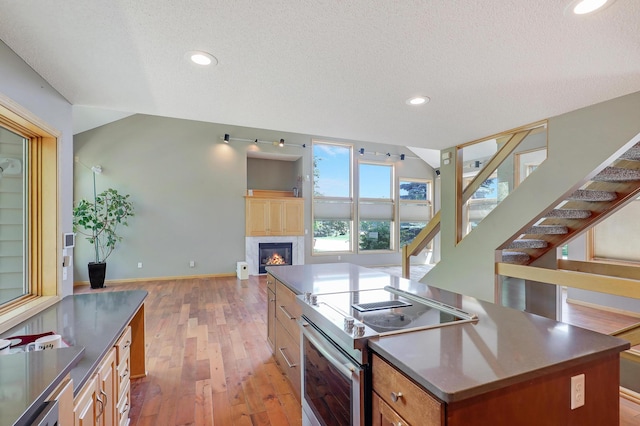 10902 Eagle Lake Blvd, Maple Grove, MN 55369 - kitchen with electric stove, a textured ceiling, open floor plan, a kitchen island, and light wood-type flooring