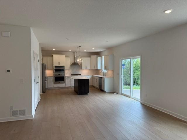 7200 Auburn Ln, Inver Grove Heights, MN 55077 - kitchen with appliances with stainless steel finishes, wall chimney range hood, light countertops, a center island, and light wood finished floors