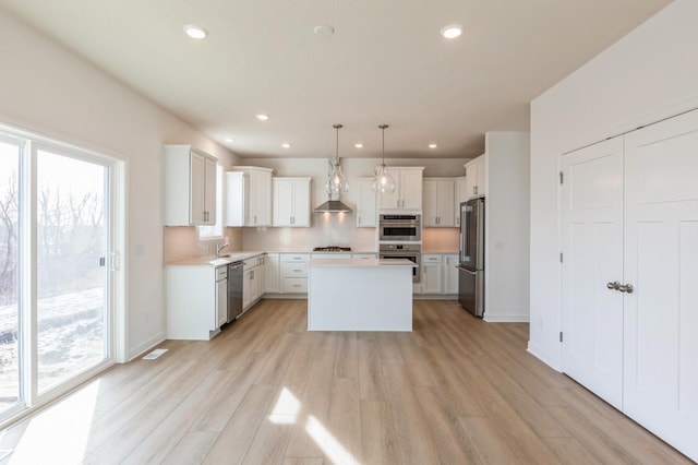 7200 Auburn Ln, Inver Grove Heights, MN 55077 - kitchen featuring stainless steel appliances, light wood-type flooring, wall chimney exhaust hood, a center island, and recessed lighting