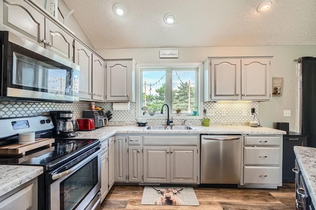 1301 English Ave NW, New Prague, MN 56071 - kitchen featuring appliances with stainless steel finishes, a textured ceiling, vaulted ceiling, tasteful backsplash, and wood finished floors