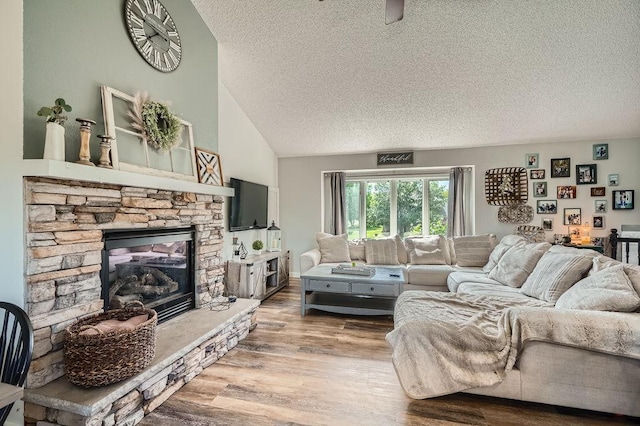 1301 English Ave NW, New Prague, MN 56071 - living room featuring a textured ceiling, wood finished floors, a stone fireplace, and vaulted ceiling