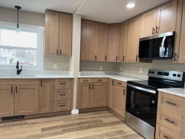 20 Erie St, Aurora, MN 55705 - kitchen with appliances with stainless steel finishes, light countertops, light wood finished floors, and hanging light fixtures