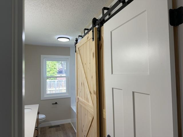 20 Erie St, Aurora, MN 55705 - bathroom featuring a textured ceiling, vanity, a tub, and wood finished floors
