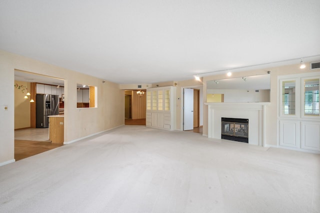 5011 Lake Ave Unit 105, White Bear Lake, MN 55110 - unfurnished living room featuring light carpet, a chandelier, a glass covered fireplace, and track lighting