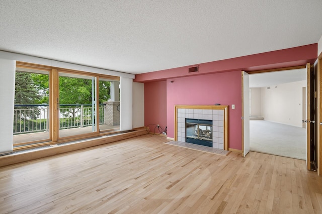 5011 Lake Ave Unit 105, White Bear Lake, MN 55110 - unfurnished living room featuring wood finished floors, a textured ceiling, and a tile fireplace