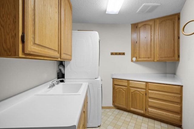 5011 Lake Ave Unit 105, White Bear Lake, MN 55110 - laundry room featuring cabinet space, stacked washer / drying machine, and a textured ceiling