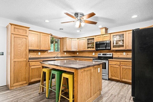 4984 Tower Rd, Moose Lake, MN 55767 - kitchen with appliances with stainless steel finishes, light wood-style flooring, a breakfast bar, a textured ceiling, and glass insert cabinets