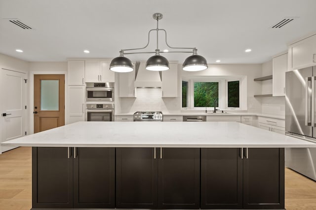2022 Lake Rd, Minnetonka Beach, MN 55391 - kitchen with stainless steel appliances, white cabinets, custom range hood, decorative backsplash, and a spacious island