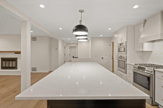 2022 Lake Rd, Minnetonka Beach, MN 55391 - kitchen with stainless steel range with gas stovetop, custom exhaust hood, a kitchen island, light wood-style flooring, and white cabinetry
