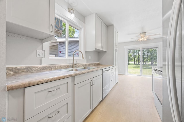1031 7th St W, West Fargo, ND 58078 - kitchen with freestanding refrigerator, white cabinets, ceiling fan, and plenty of natural light