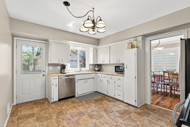 4128 Zane Ave N, Robbinsdale, MN 55422 - kitchen with stainless steel appliances, a chandelier, light countertops, white cabinets, and stone finish flooring