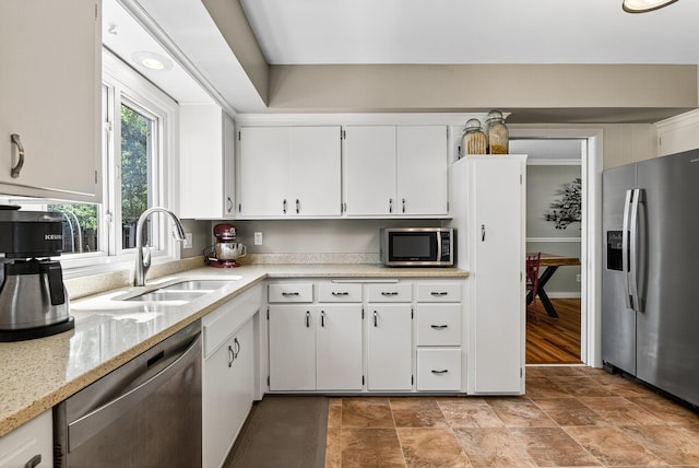 4128 Zane Ave N, Robbinsdale, MN 55422 - kitchen with appliances with stainless steel finishes, white cabinetry, light stone countertops, and stone finish flooring