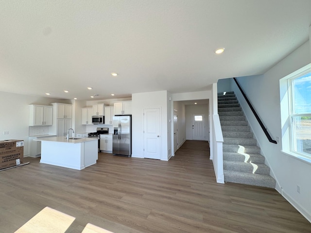 2455 Jandell Ave NE, Saint Michael, MN 55376 - kitchen with stainless steel appliances, open floor plan, light wood-type flooring, white cabinetry, and an island with sink