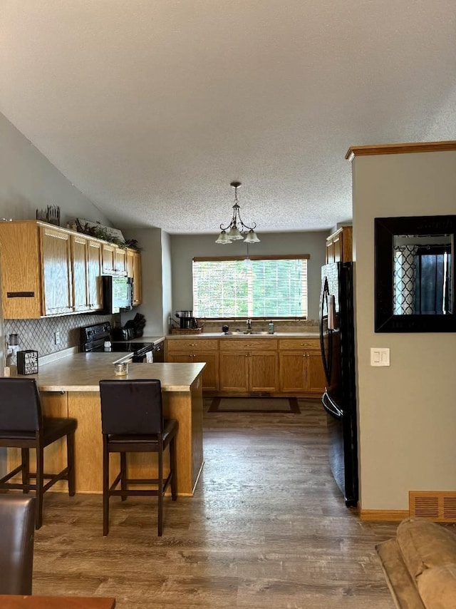 608 11th Ave SW, Rice, MN 56367 - kitchen featuring black appliances, a peninsula, a chandelier, and dark wood-style flooring