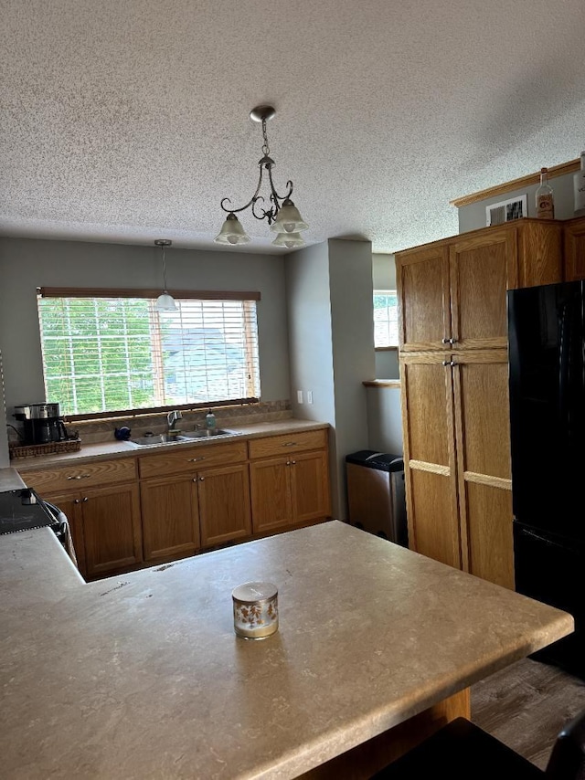 608 11th Ave SW, Rice, MN 56367 - kitchen featuring black appliances, brown cabinets, a textured ceiling, decorative light fixtures, and a peninsula