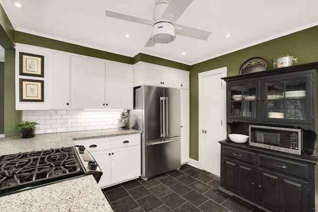 1064 Lombard Ave, Saint Paul, MN 55105 - kitchen featuring appliances with stainless steel finishes, a ceiling fan, white cabinets, tasteful backsplash, and ornamental molding