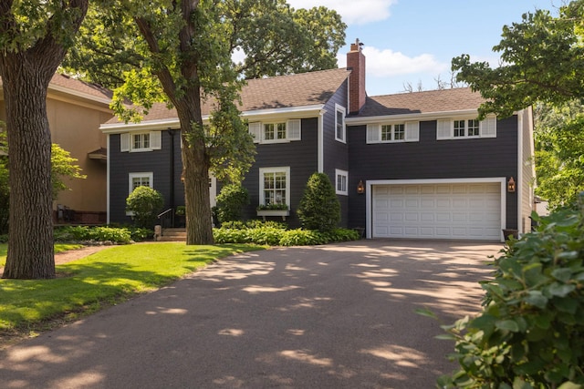 1064 Lombard Ave, Saint Paul, MN 55105 - view of front of house featuring driveway, a garage, a chimney, and a front lawn