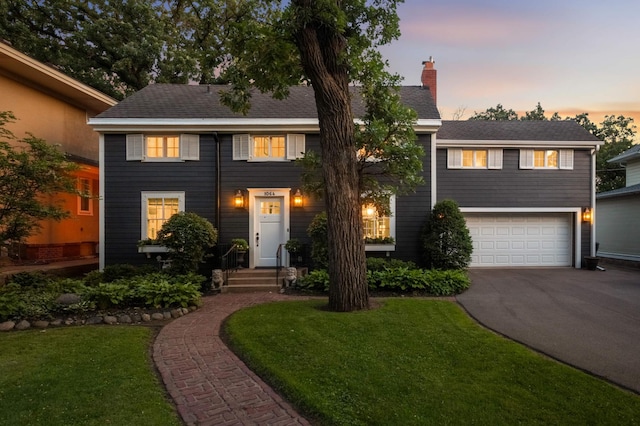 1064 Lombard Ave, Saint Paul, MN 55105 - view of front of home featuring asphalt driveway, an attached garage, a chimney, and a front lawn