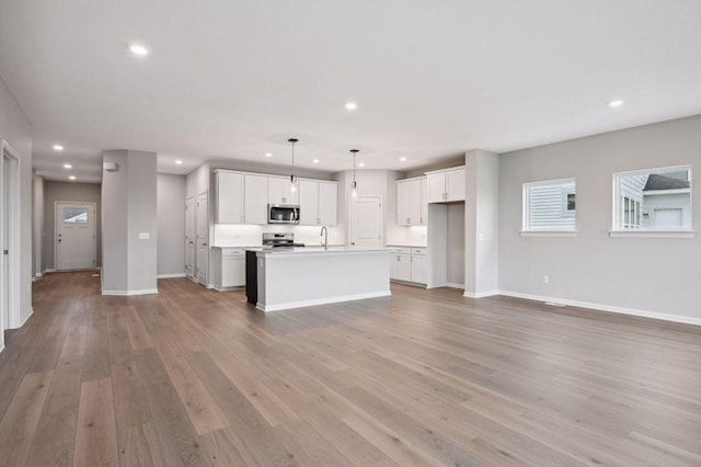 1682 Tyrone Dr, Shakopee, MN 55379 - kitchen featuring stainless steel microwave, stove, recessed lighting, open floor plan, and a center island with sink