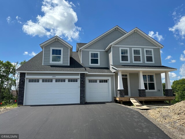 17205 61st St NE, Otsego, MN 55330 - view of front facade featuring asphalt driveway, covered porch, a shingled roof, and stone siding