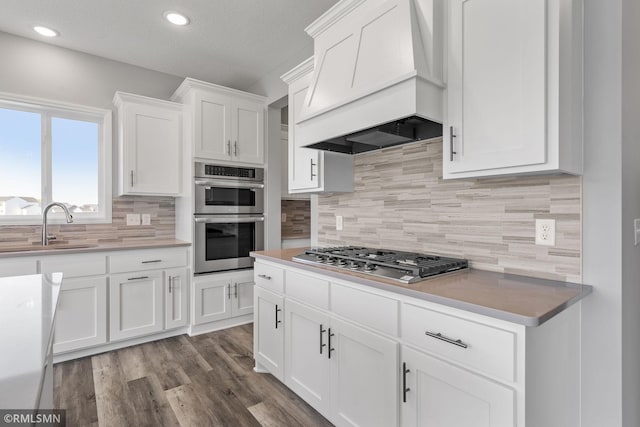 17205 61st St NE, Otsego, MN 55330 - kitchen with appliances with stainless steel finishes, custom exhaust hood, backsplash, white cabinetry, and recessed lighting