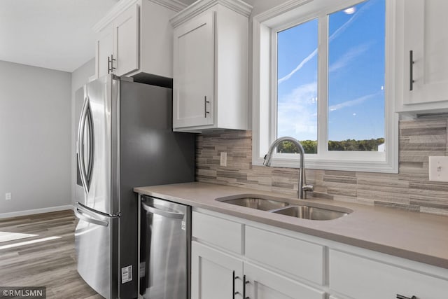 17205 61st St NE, Otsego, MN 55330 - kitchen with appliances with stainless steel finishes, tasteful backsplash, white cabinetry, light countertops, and wood finished floors